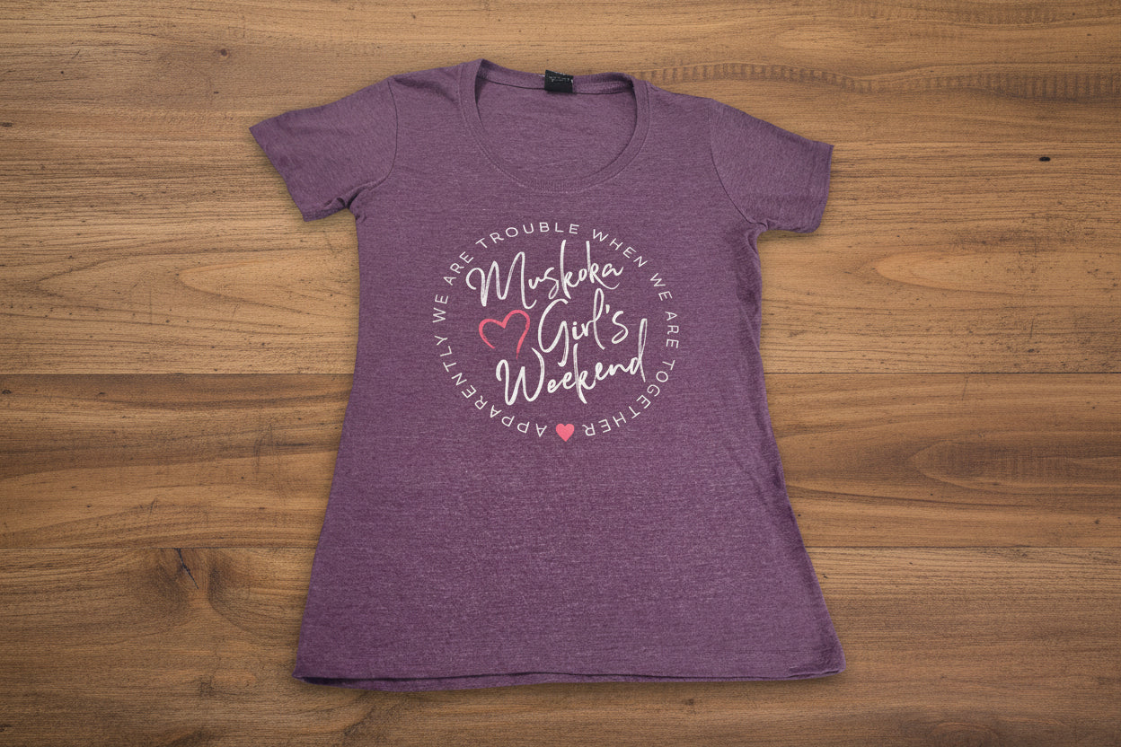 A purple short-sleeved t-shirt with the text 'Muskoka Girls Weekend' printed on the front.