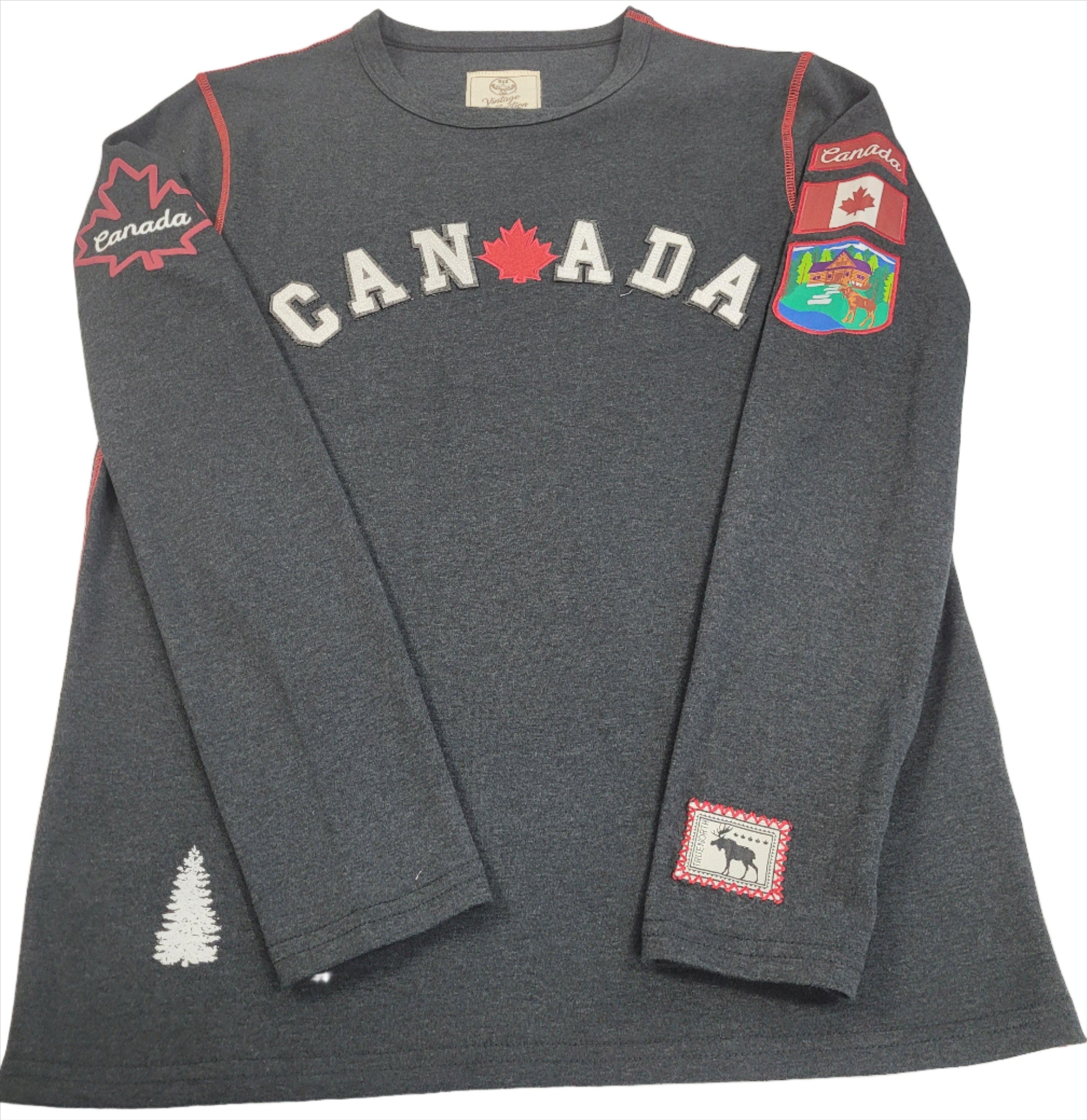 A long sleeve grey t-shirt with the word 'CANADA' printed across the chest and additional Canada-themed graphics on the sleeves and bottom hem.