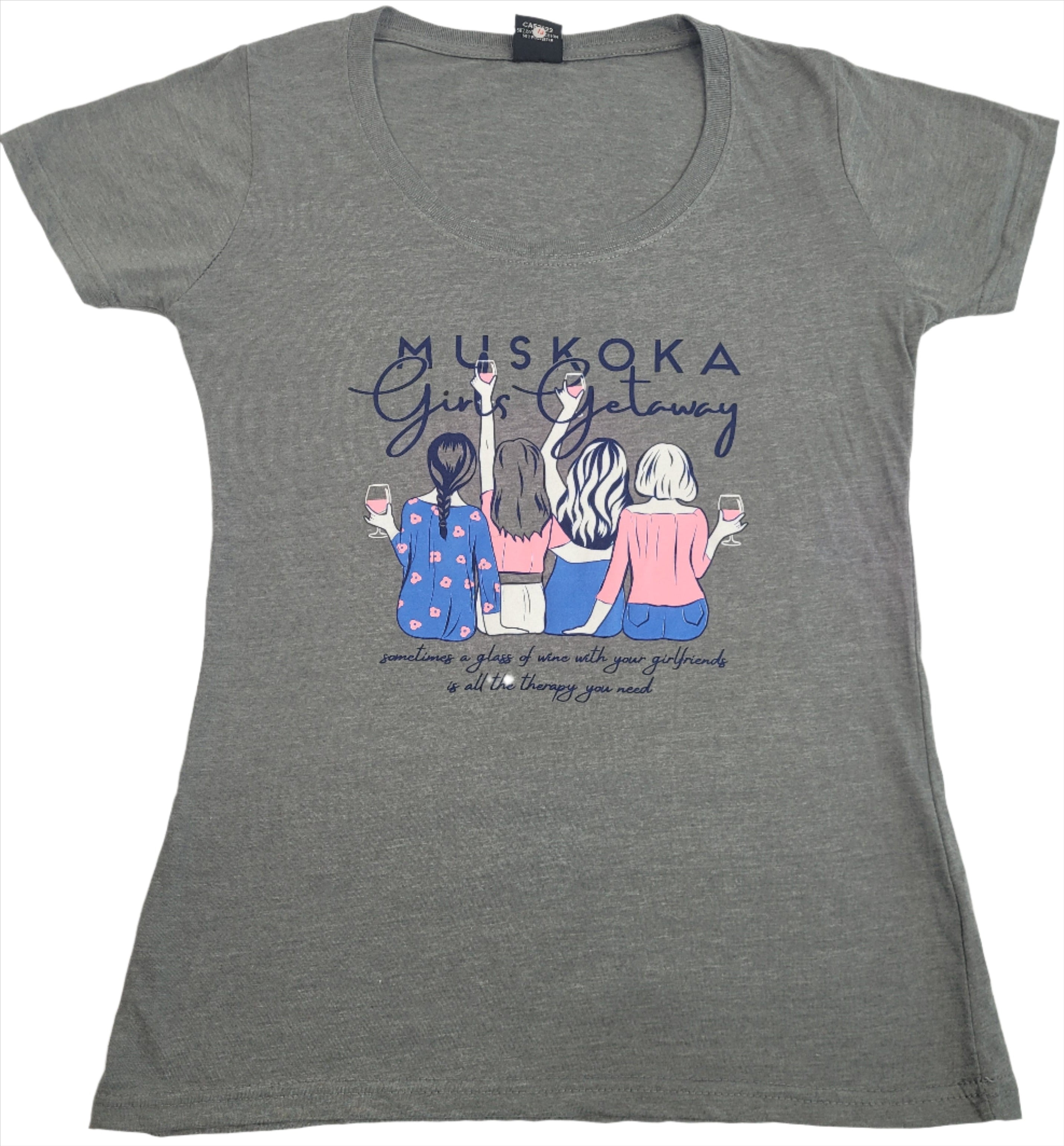 A gray t-shirt with text 'MUSKOKA Girls Getaway' and an illustration of three women wearing hats and holding coffee cups.