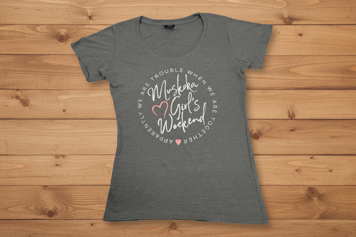 A light grey t-shirt with the text 'Muskoka Girls Weekend' and heart graphics printed on the front.
