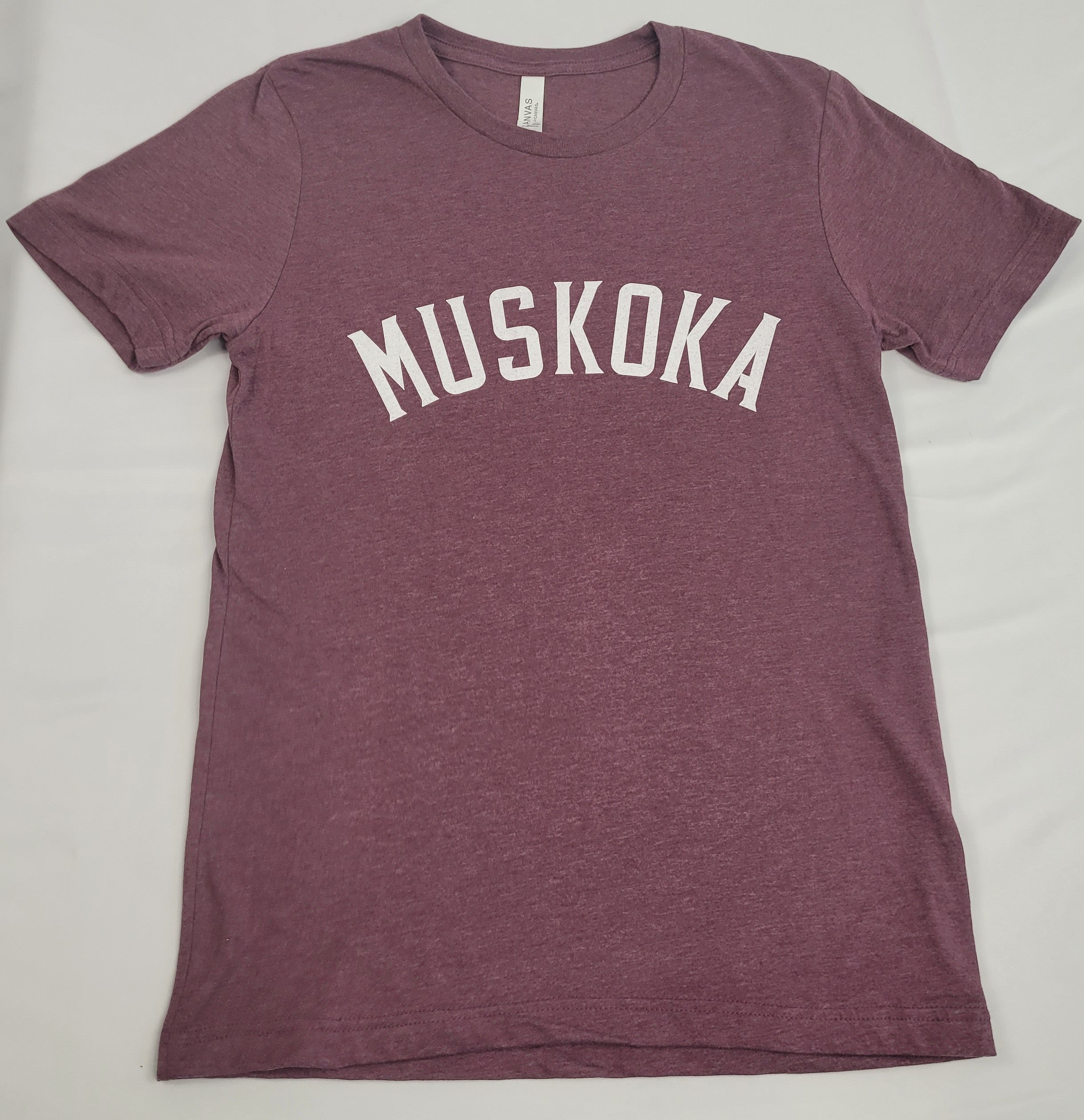 A burgundy short-sleeved T-shirt with the text 'MUSKOA' printed in white on the front.
